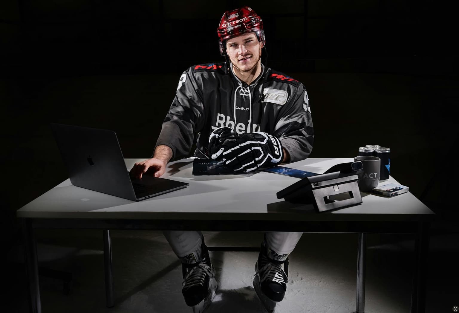 Spieler der Kölner Haie an einem Tisch in einem dunklen Raum