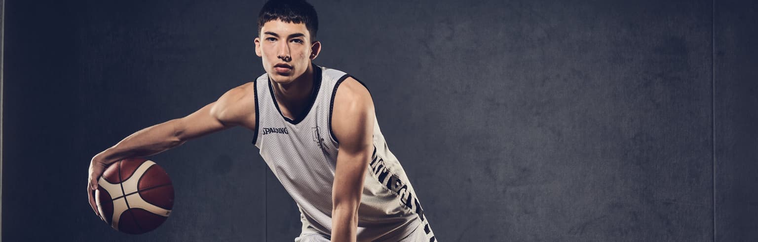 Probaskets Profispieler mit einem Basketball vor einer Leinwand.